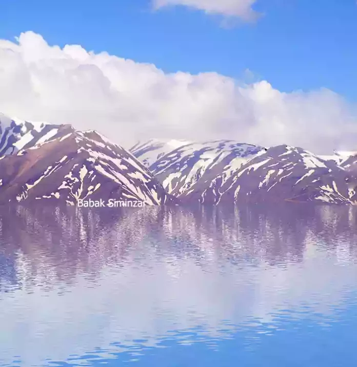 A landscape photo of water reflection of snowy mountains and clouds